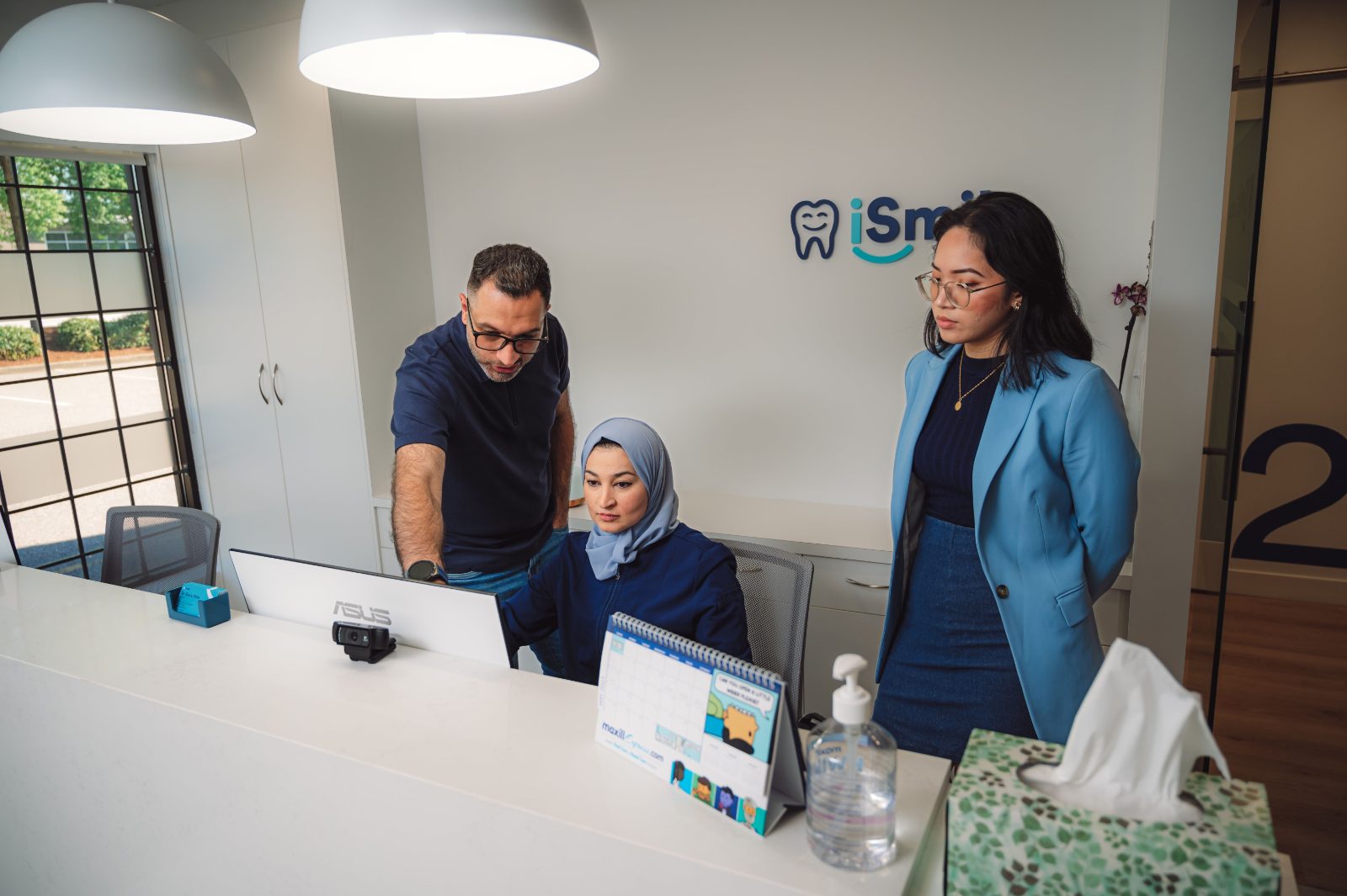 Estella, Kareem and Dr. Rania Ataia at the reception desk of iSmile Dental in Langley, BC