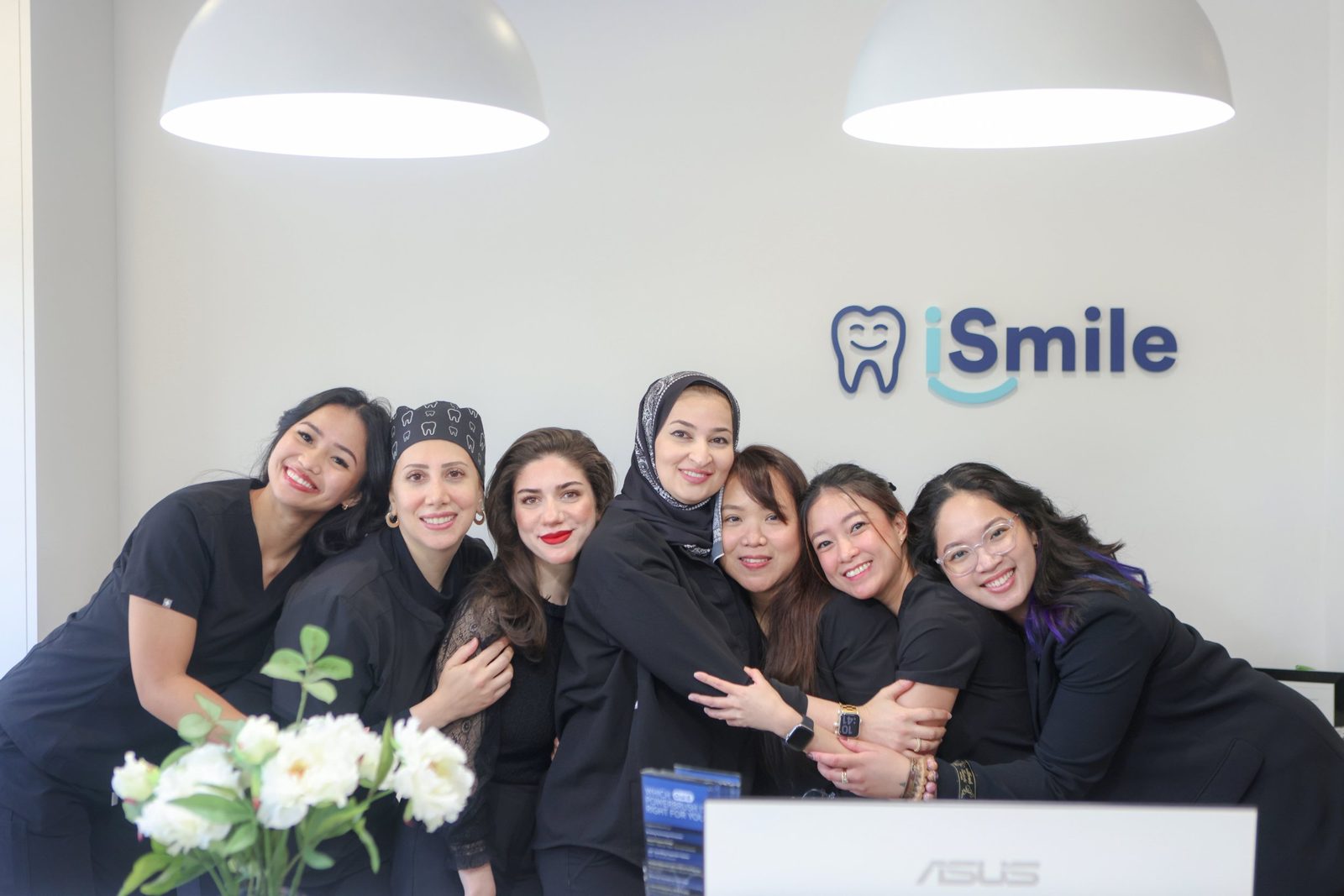 iSmile Dental team members sharing a group hug at the front reception desk in Langley, BC